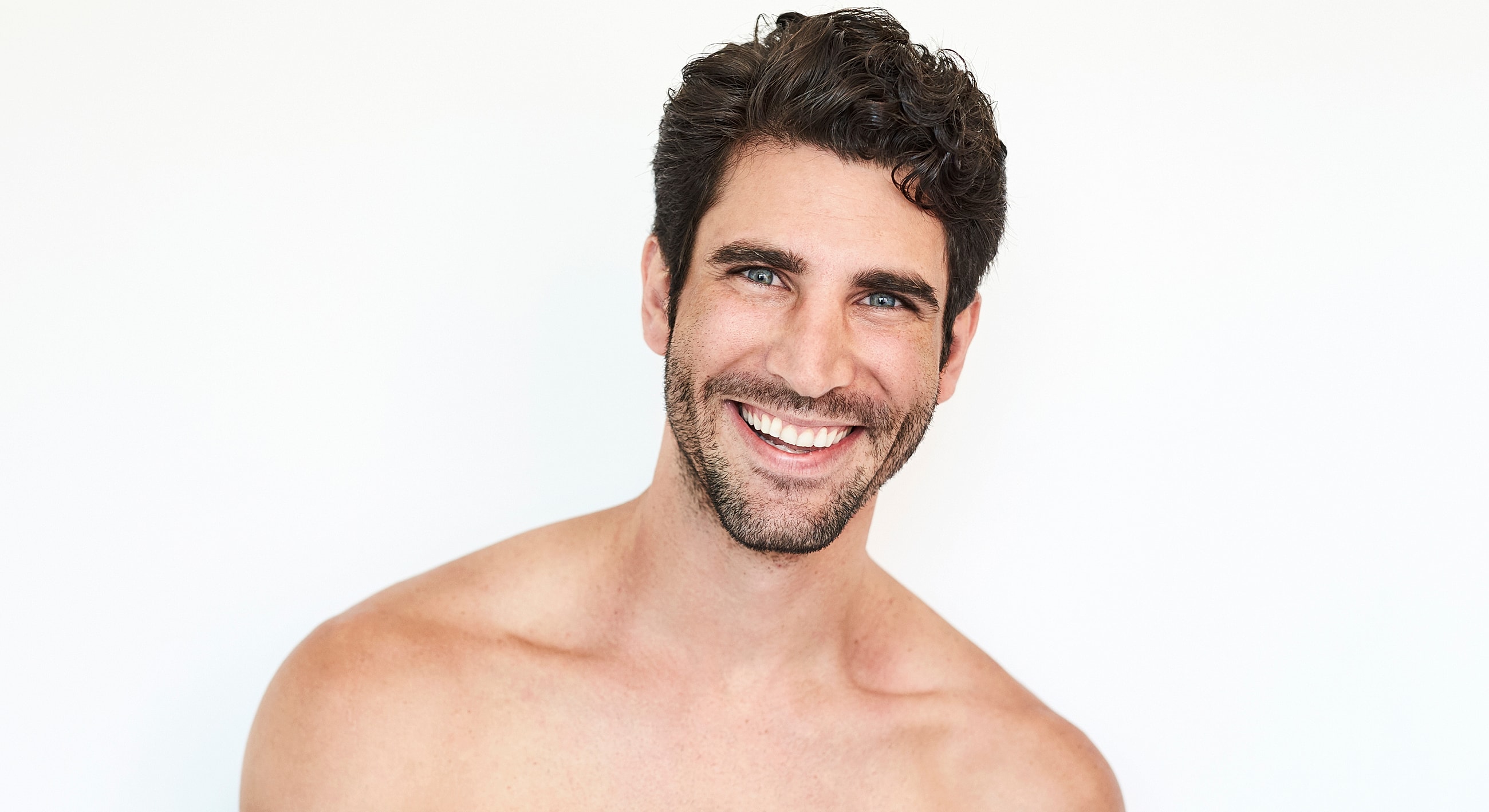 Smiling man with curly hair and bare shoulders.